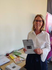 the student holding up their project and smiling