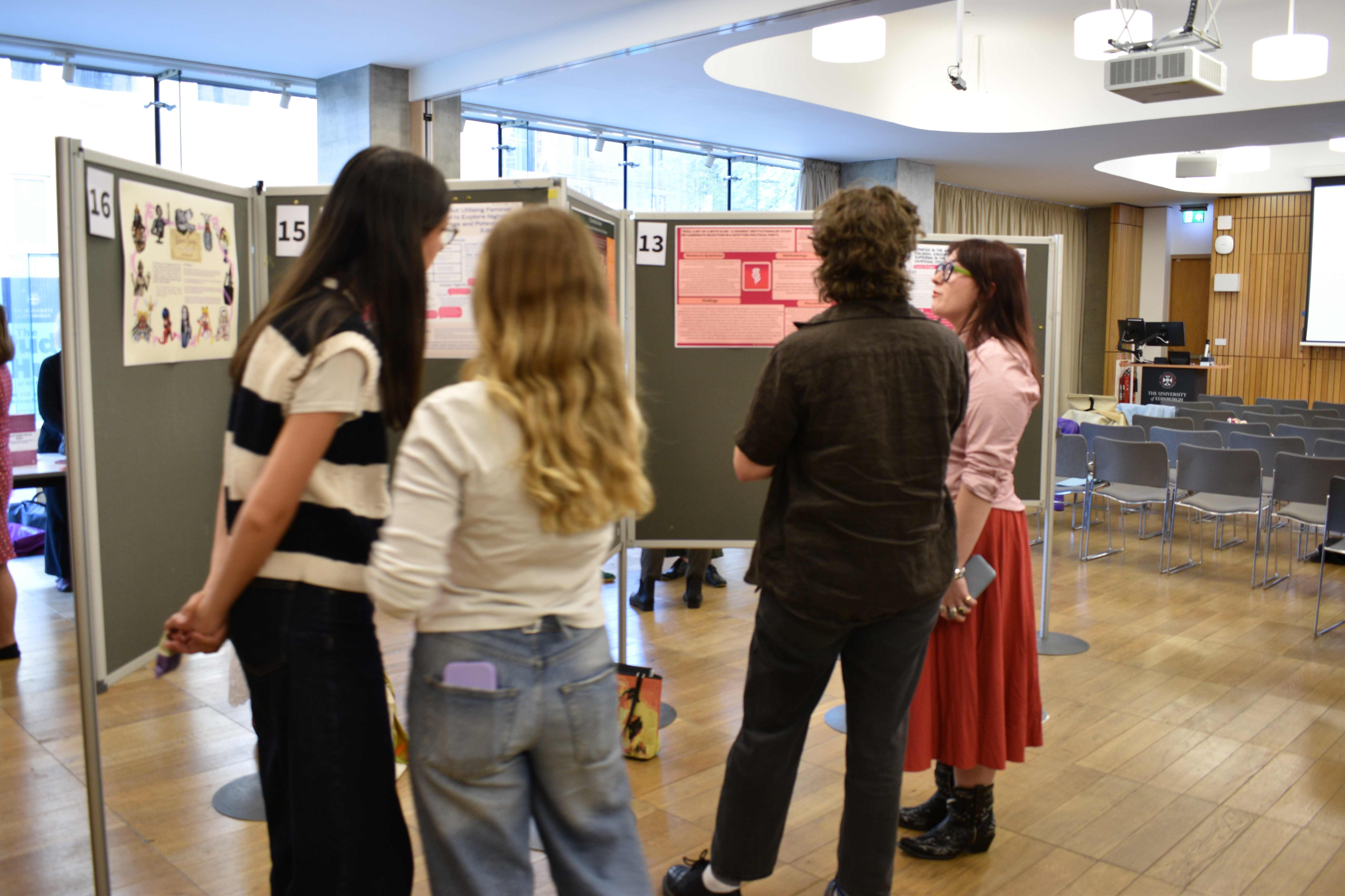 Four people looking at the posters of the undergraduate dissertation showcase.