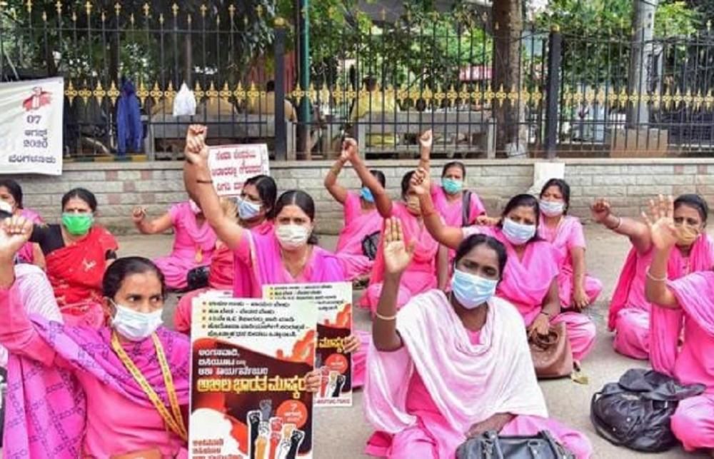 ASHA Workers wearing pink, sitting down in protest