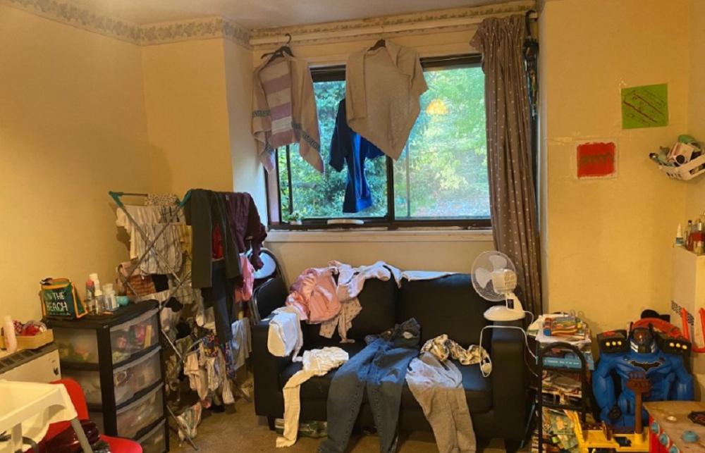 Picture of clothes laying out on a sofa to dry. More clothes hang above the sofa, and on a clothes horse beside it