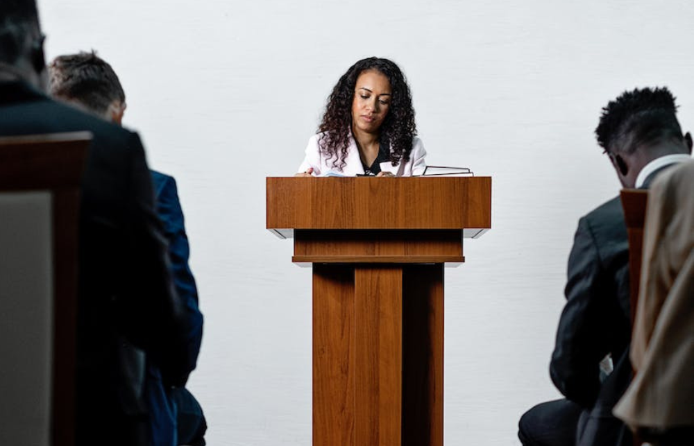 A black woman stands at a lectern to deliver a speech