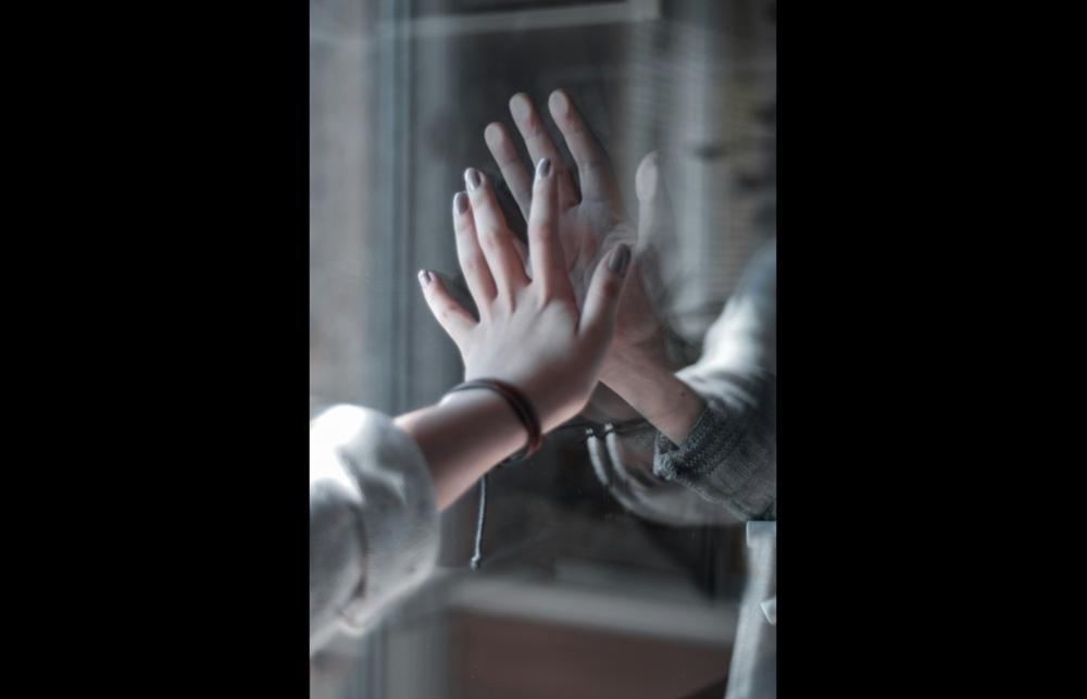 A woman's arm with a silver and red bracelet, poised against a mirror
