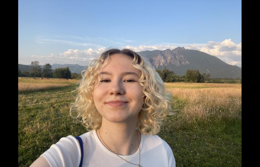 Photo of Emmi Wilkinson against rural hilly background.