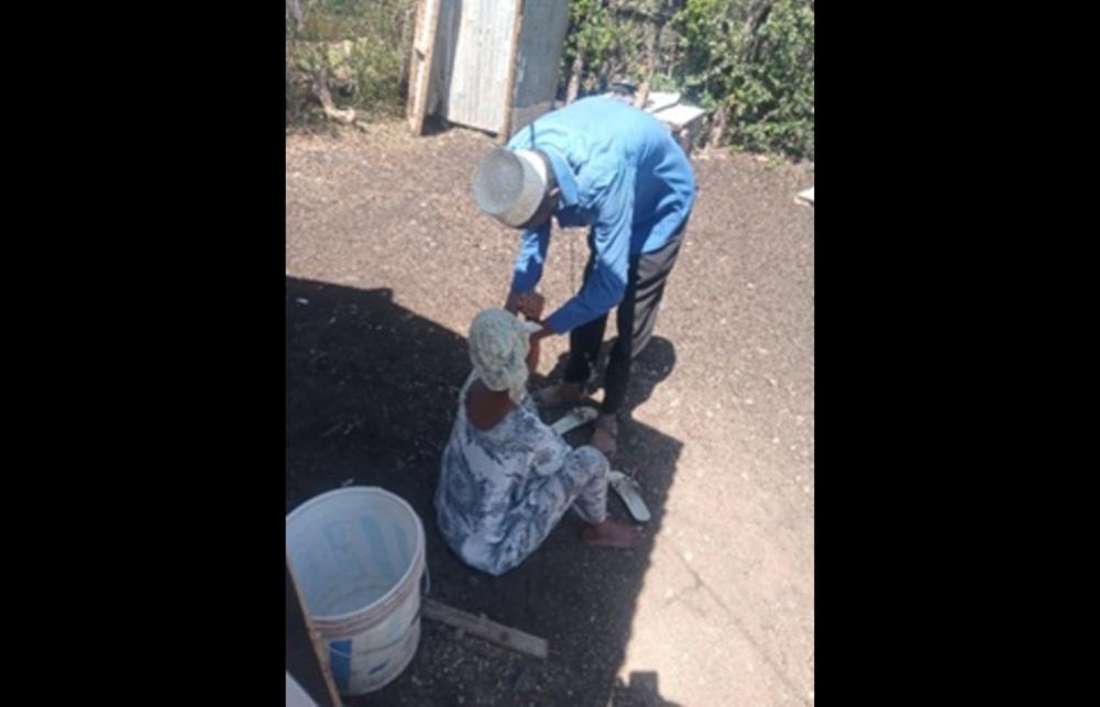 A male Community Health Volunteer in Isiolo, northern Kenya, bends down to check a community member.